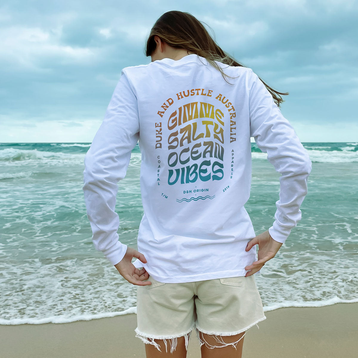 The unisex Long Sleeve Tee, in white, modelled by Em